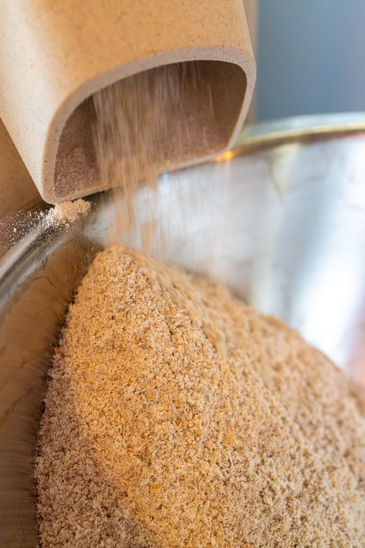 A close up freshly ground flour, coming out of the chute of a stone grinder